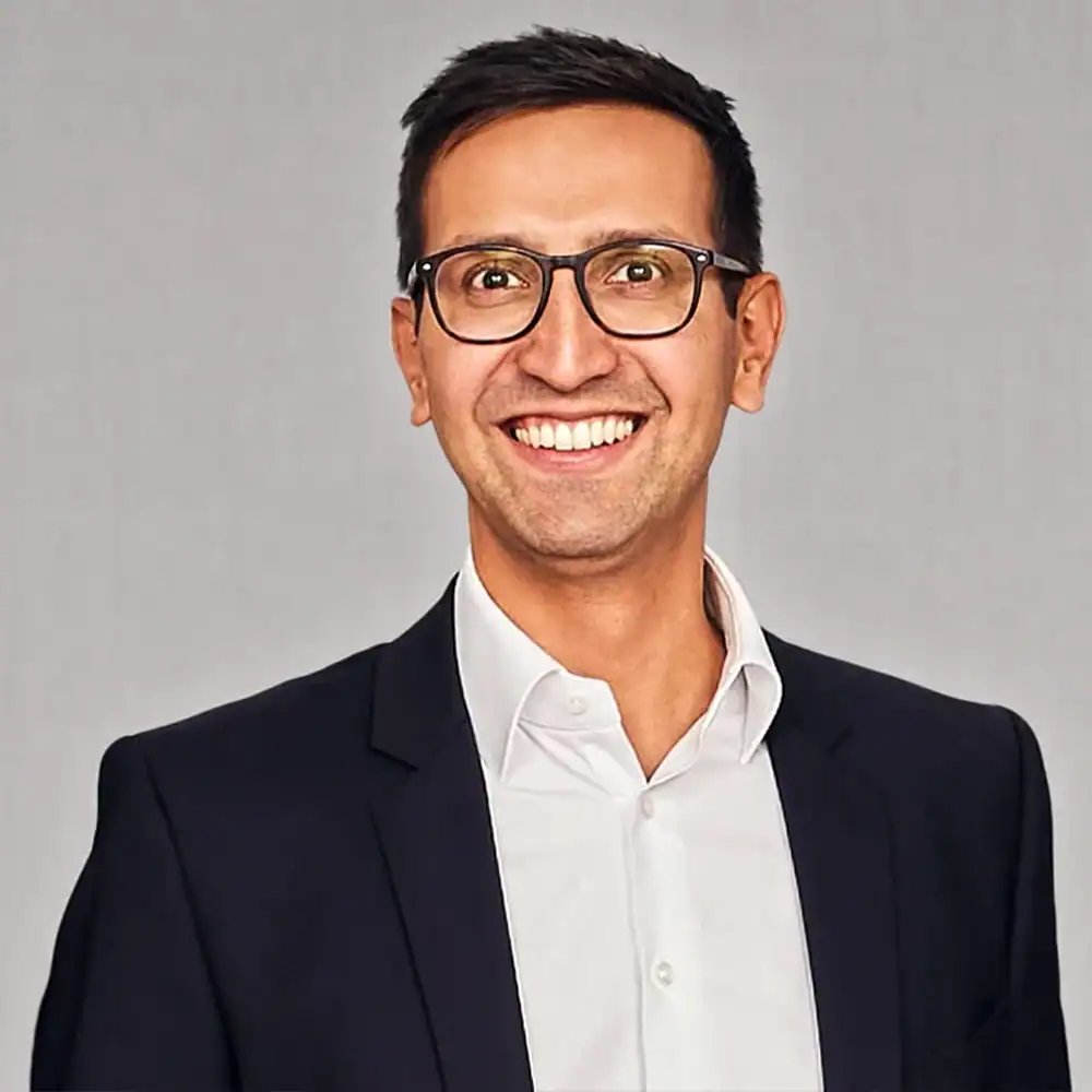 Geschäftsmann in Anzug mit Brille, lächelnd, professionell.