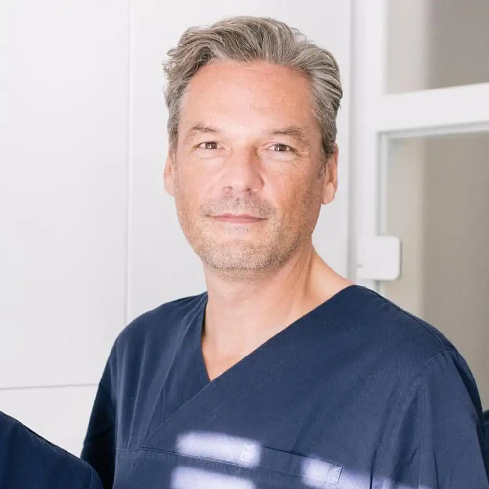 DokFee Arzt in Praxis mit freundlichem Blick und professionellem Auftreten.