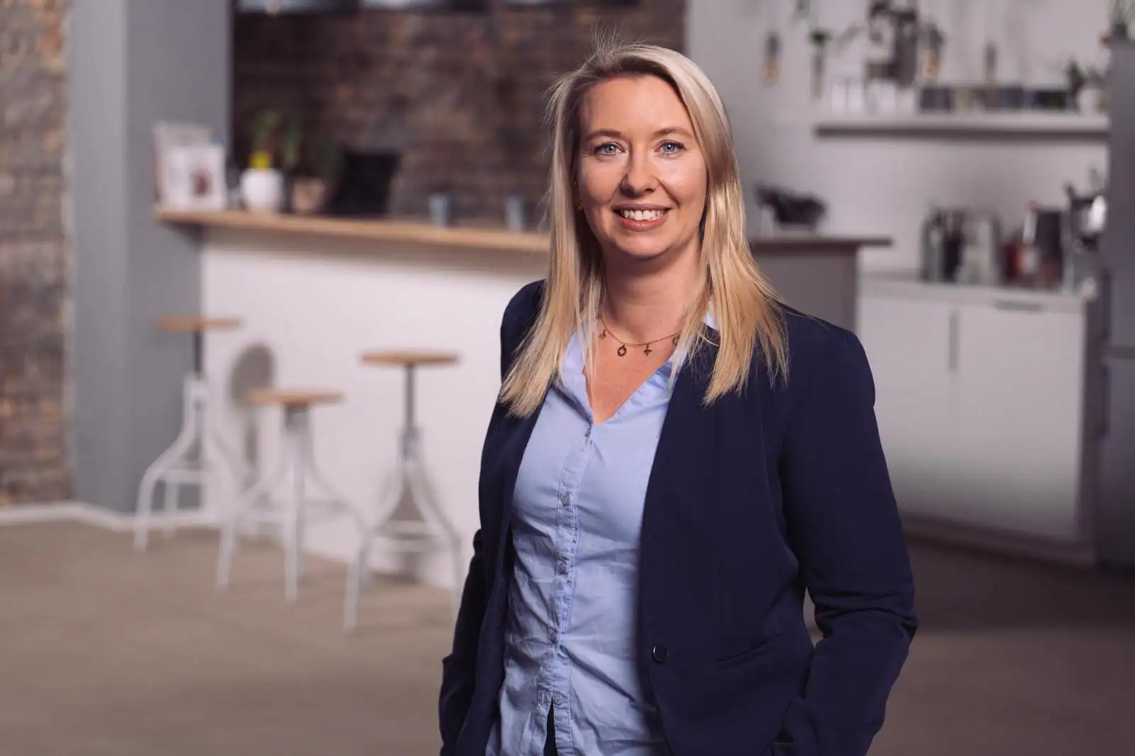 Frau in Businesskleidung vor modernem Bürohintergrund.